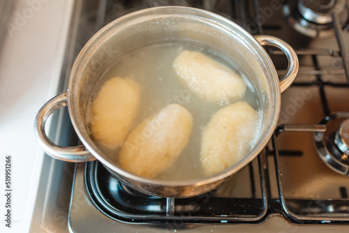 Traditional Lithuanian stuffed potato dumplings in the pot water. The dumplings are made from grated and riced potatoes and stuffed with ground meat.Indoors shot. © ARVD73
