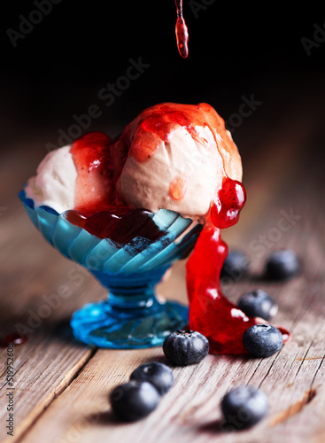 ice cream balls with strawberry jam and blueberries on a table made of vintage boards