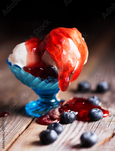 ice cream balls with strawberry jam and blueberries on a table made of vintage boards