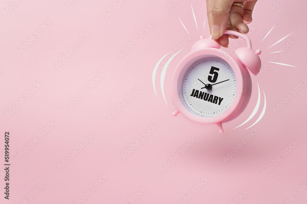 Obraz premium January 5th. Day 5 of month, Calendar date. The morning alarm clock jumping up from the bell with calendar date on a pink background. Winter month, day of the year concept.