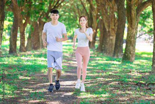 young couple jogging together in the park on sunny day