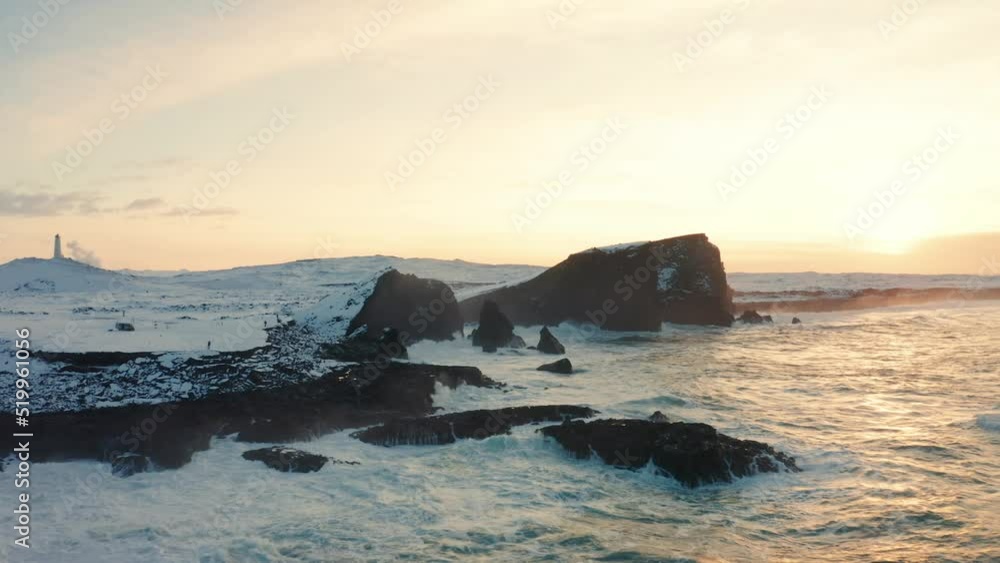 A drone shot a beautiful sunset in Iceland while the waves hit the black sand and the clouds covering the sky A drone shot a beautiful sunset in Iceland while the waves hit the black sand and the clouds covering the sky