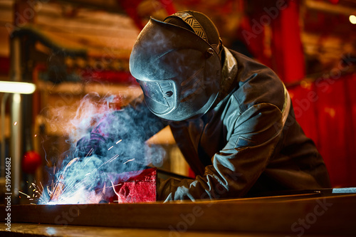 Laborer in protective mask welds manually metal frame