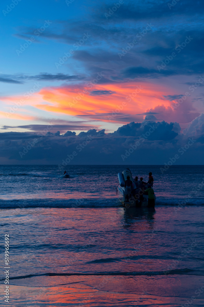 Beautiful bright sunset with colored clouds in the sky over the sea, ocean. Silhouette boat in the sea, lush clouds. Summer tropical natural background. Travel concept. Thailand, Phuket island