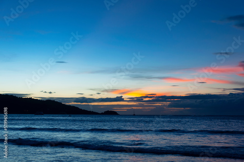 Beautiful bright sunset with colored clouds in the sky over the sea  ocean. Silhouette boat in the sea  lush clouds. Summer tropical natural background. Travel concept. Thailand  Phuket island