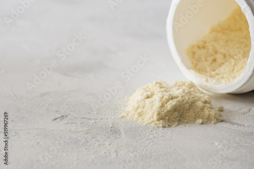 Bovine colostrum powder spilling from plastic container on table