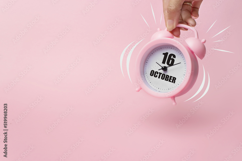 Obraz premium October 16th. Day 16 of month, Calendar date. The morning alarm clock jumping up from the bell with calendar date on a pink background. Autumn month, day of the year concept.