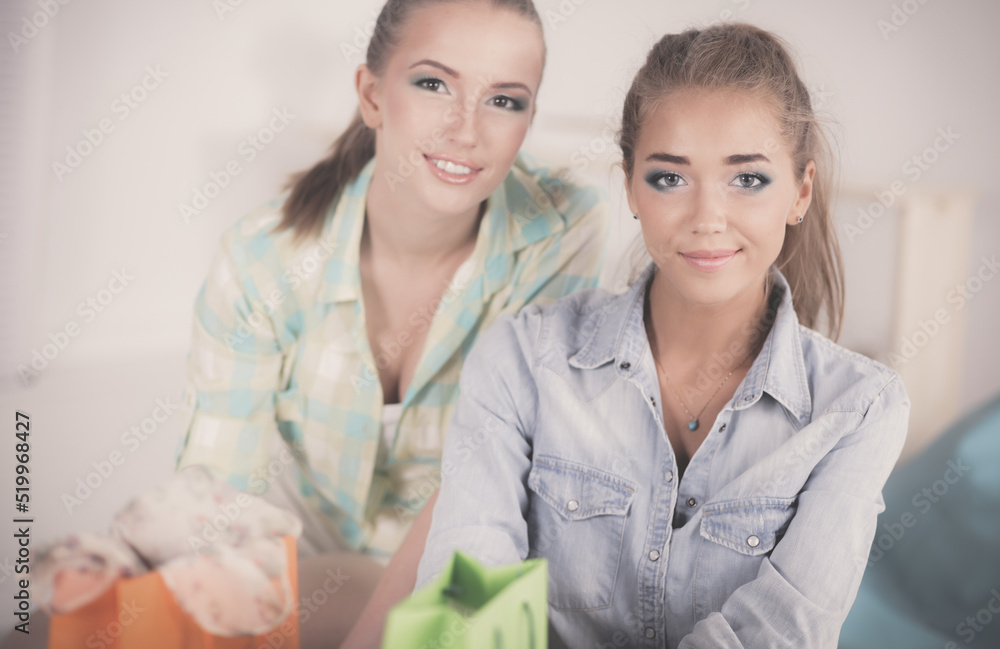 Two young women sitting with shopping bag at home Two young women sitting with shopping bag at home