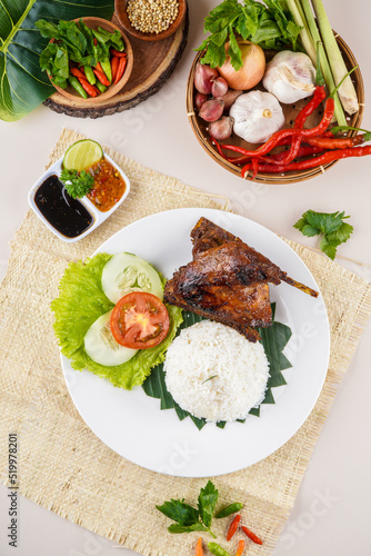 Bebek Bakar or Roasted duck with Sambal Terasi, a traditional food from Indonesia typical of West Java. This food is served with rice, cucumber, tomato and fresh vegetables.