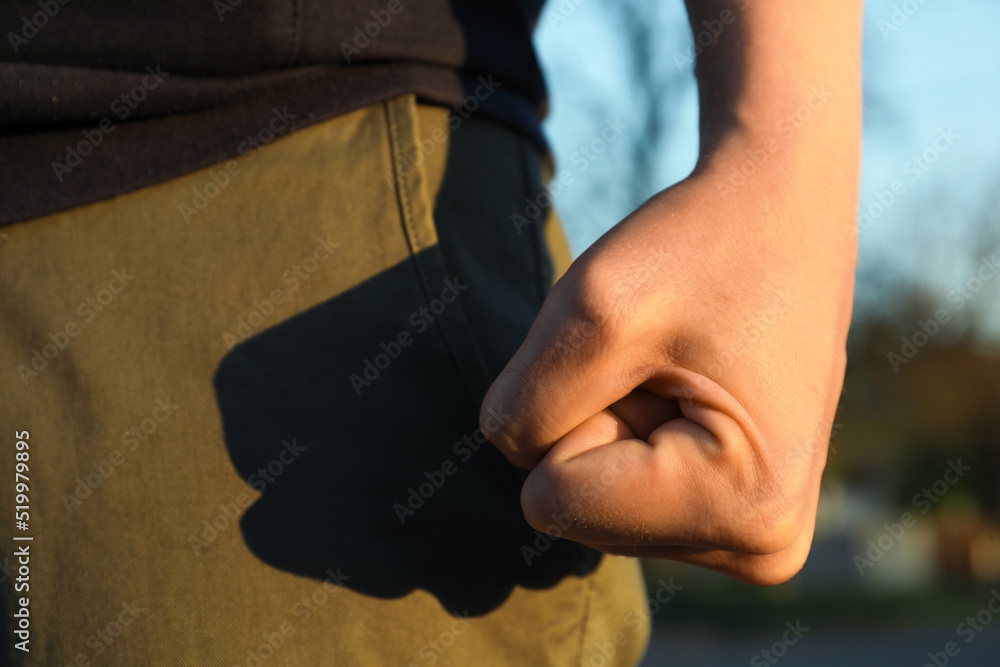 Angry man with clenched fist outdoors, closeup