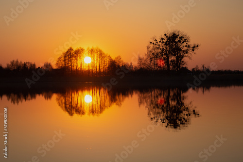 The reflection in the water of the sunset behind the trees