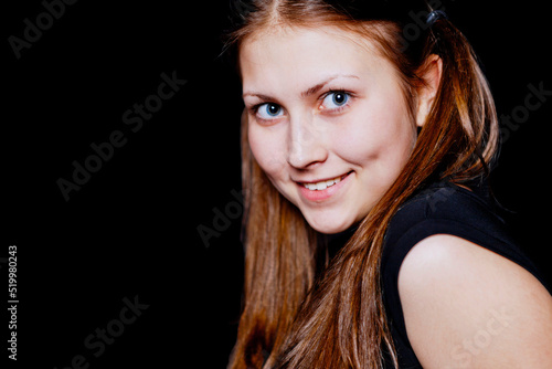 Cute girl - brunette looks at the camera. Black background