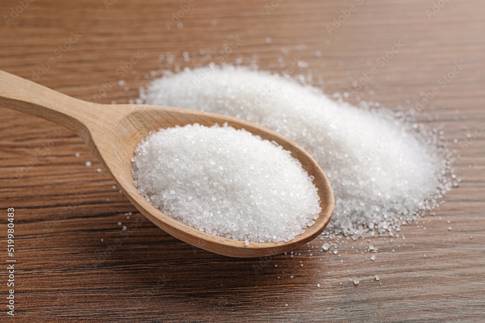 Granulated sugar and spoon on wooden table, closeup Granulated sugar and spoon on wooden table, closeup