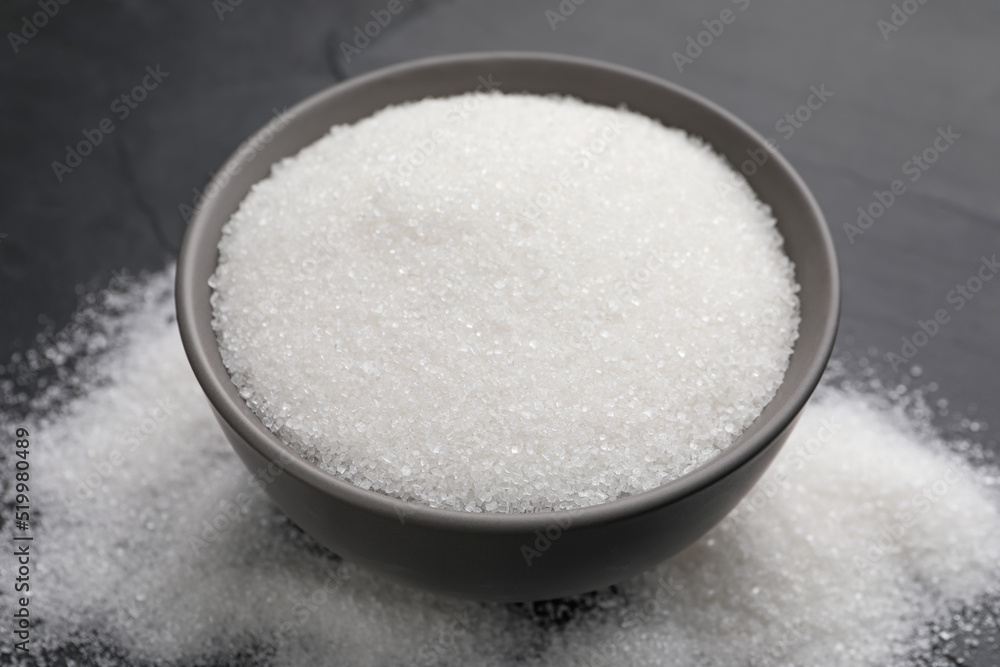 Granulated sugar on black table, closeup view Granulated sugar on black table, closeup view