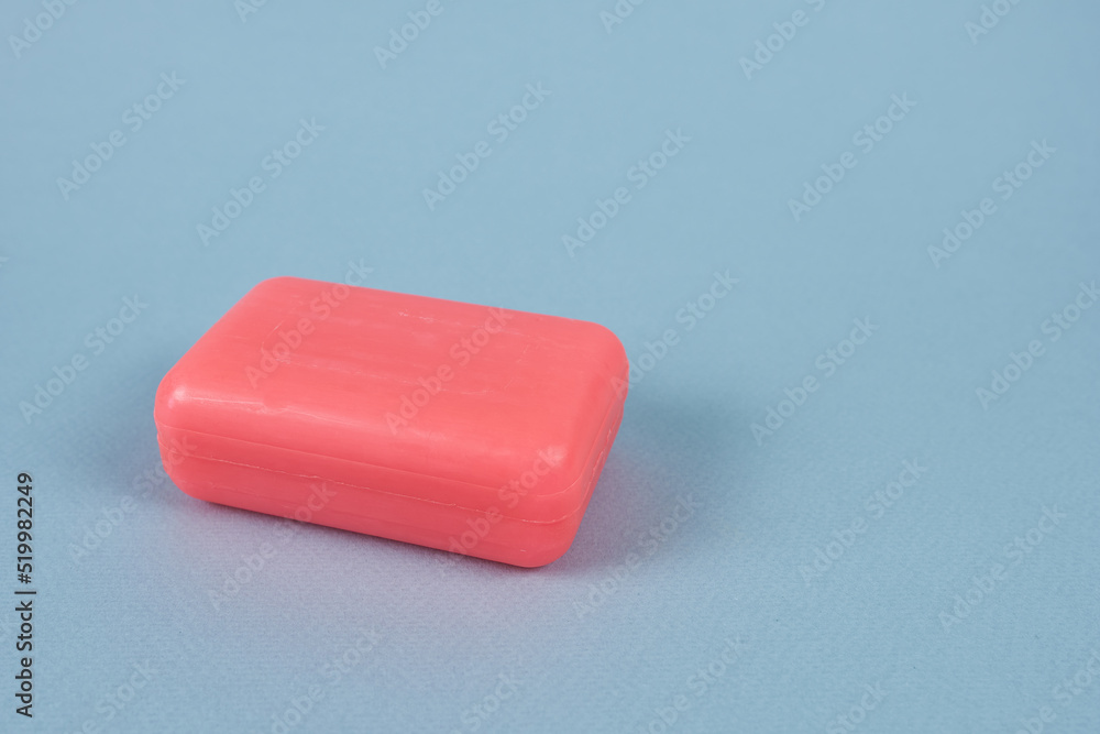 A piece of pink soap on a blue background, close-up. Detergent. A piece of pink soap on a blue background, close-up. Detergent.