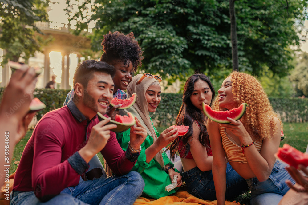 Cheerful young adults eating watermelon in park Cheerful young adults eating watermelon in park