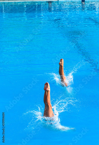 Aquatic Pool Diving Girls Pairs Action Half and Half Entry Into Blue Waters.