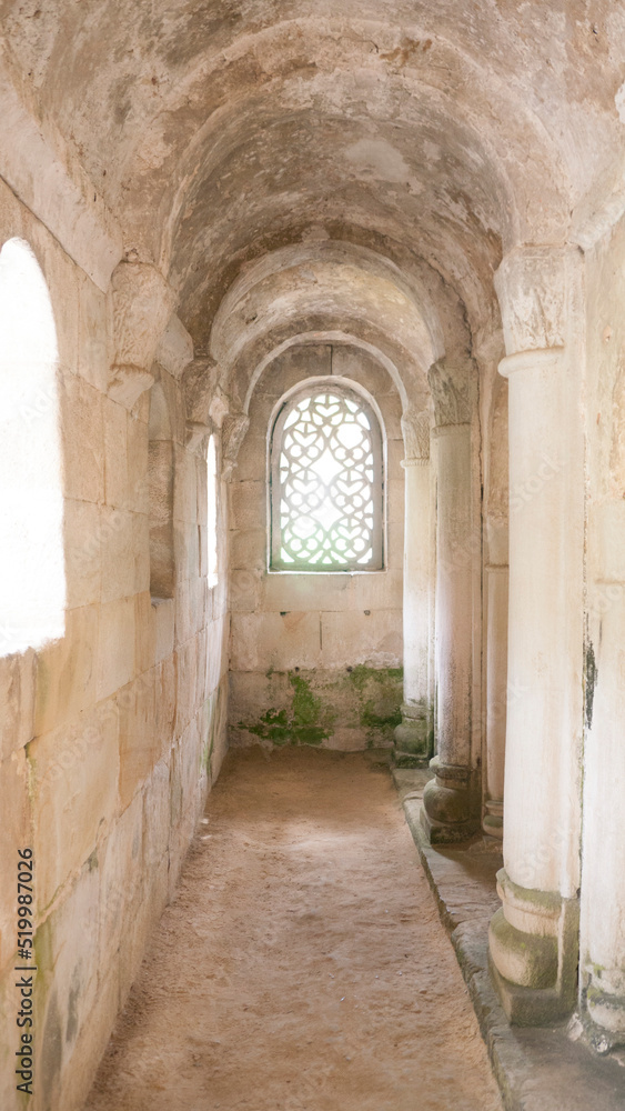 Ventana con celosía en arco de medio punto en pasillo de iglesia románica de piedra