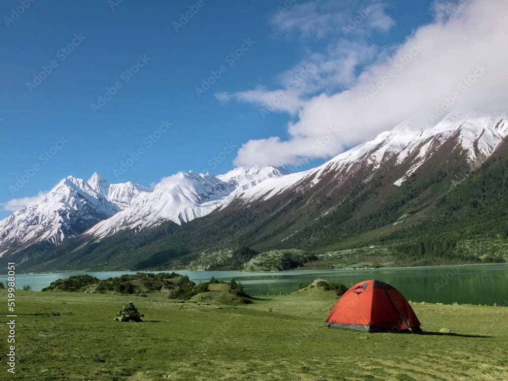 Red tent and snow-capped green mountains