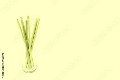 Bamboo straws in a glass against light yellow background