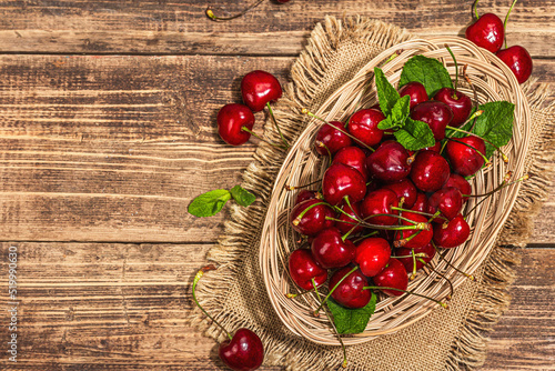Ripe sweet cherries with fresh mint leaves, traditional summer fruits. Trendy light, vintage napkin