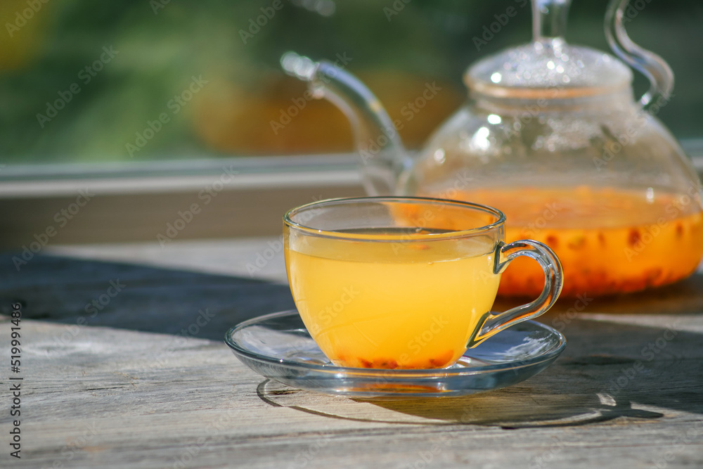 Sea buckthorn tea in glass cups and teapot on a wooden windowsill. Healthy vitamin drink Sea buckthorn tea in glass cups and teapot on a wooden windowsill. Healthy vitamin drink
