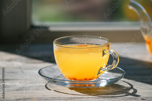 Sea buckthorn tea in a glass cup on a wooden windowsill. Healthy vitamin drink