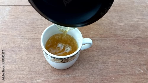 person filling the cup of  green tea