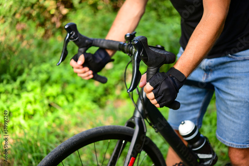 Male hands holding a handlebars of a bicycle. Man riding bicycle in nature
