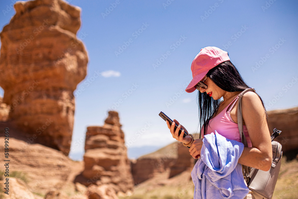 girl standing with a phone on the background of a blurred canyon