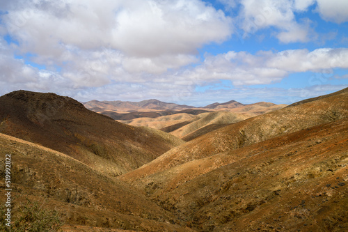 Hilly terrain against cloudy sky