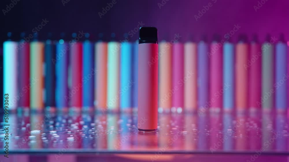 Lots of E-Cigarettes and Vapes with Smoke in Neon Lighting. Concept of Bad Habits. Modern Smoking Electronic Cigarettes. Slow Motion Lots of E-Cigarettes and Vapes with Smoke in Neon Lighting. Concept of Bad Habits. Modern Smoking Electronic Cigarettes. Slow Motion