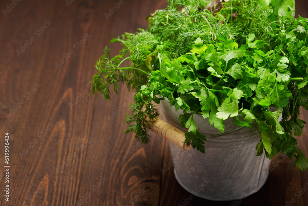 a bunch of green dill, parsley, salad and other greens in an iron bucket, dark wooden background, concept of fresh vegetables and healthy food a bunch of green dill, parsley, salad and other greens in an iron bucket, dark wooden background, concept of fresh vegetables and healthy food
