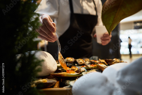 waiter adding sauce on mussels during catering