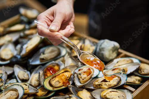waiter adding sauce on mussels during catering