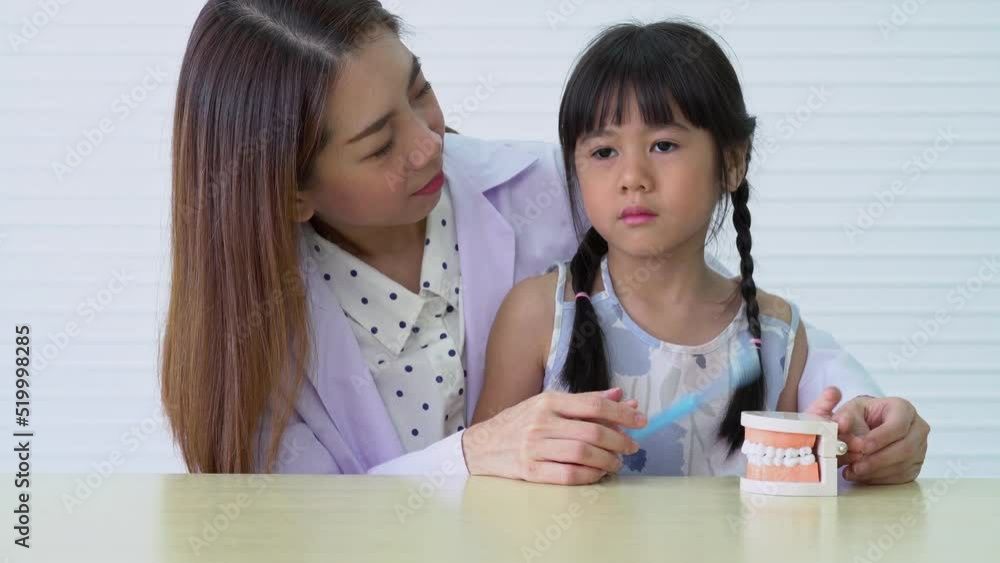 Asian female dentist teaching cute little girl brushing teeth with toothbrush and stomatologist telling girl child about oral hygiene in dental clinic, Education and prevention cavities concept. Asian female dentist teaching cute little girl brushing teeth with toothbrush and stomatologist telling girl child about oral hygiene in dental clinic, Education and prevention cavities concept.