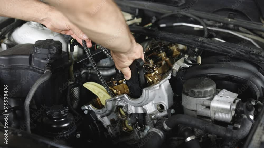 Car mechanic repair the engine in a car service. Unrecognizable mechanic repairing automobile motor using tool. Auto master fixing engine from vehicle. Repairer working in garage or workshop Car mechanic repair the engine in a car service. Unrecognizable mechanic repairing automobile motor using tool. Auto master fixing engine from vehicle. Repairer working in garage or workshop
