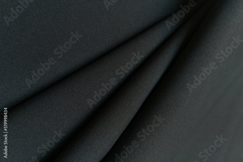 Gray crumpled or wavy fabric texture background. Abstract linen cloth soft waves. Gabardine wool fabric. Merino yarn. Smooth elegant luxury cloth texture. Concept for banner or advertisement.
