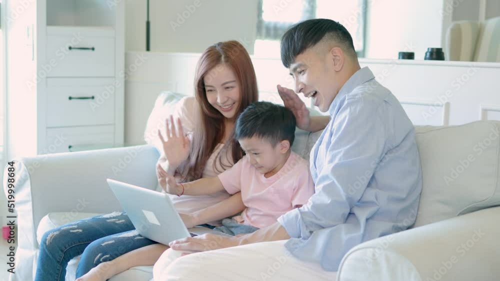 Happy family and kid waving hands looking at web camera using laptop for video call Happy family and kid waving hands looking at web camera using laptop for video call