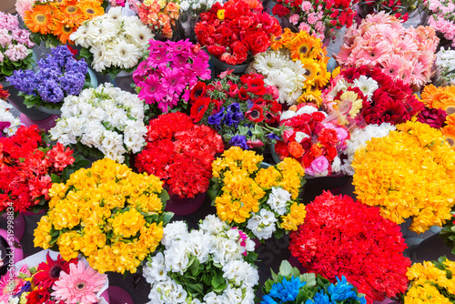Close shot of colorful flowers displayed on street in vases