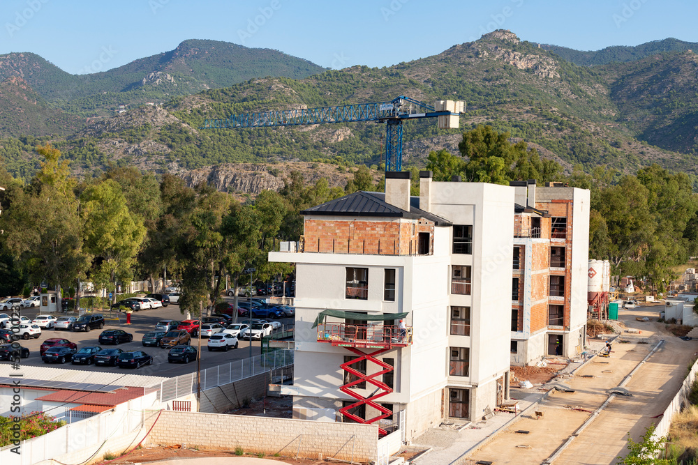 Building. Building under construction with a crane. Mountainous landscape in the background. Horizontal photography.