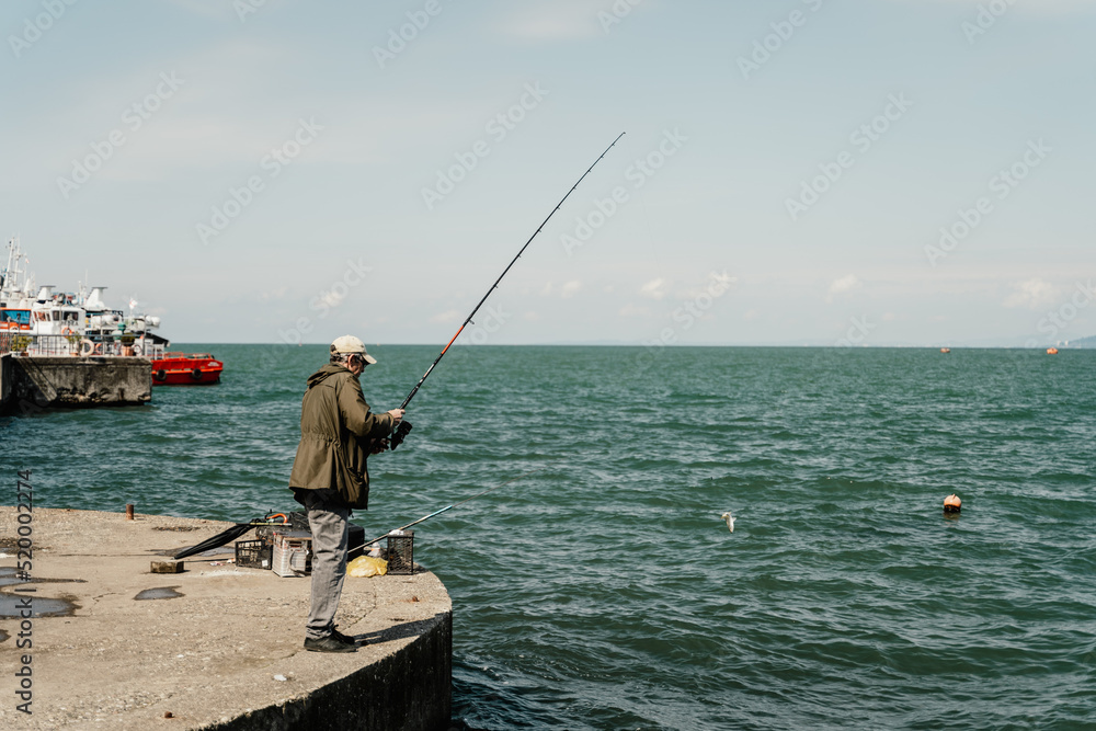 Batumi, Georgia - 04.05.2021: Fisherman fishing near Batumi seaport