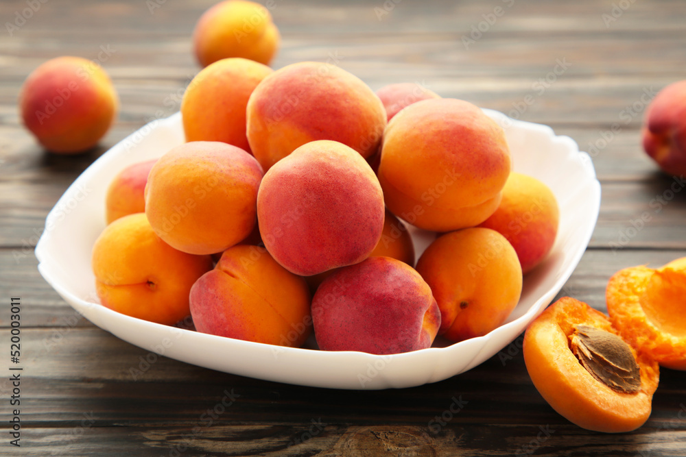Fresh apricots in the bowl on brown wooden background Fresh apricots in the bowl on brown wooden background