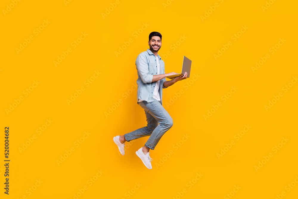 Full length photo of cheerful skilled man guy jump up use device laptop isolated on yellow color background