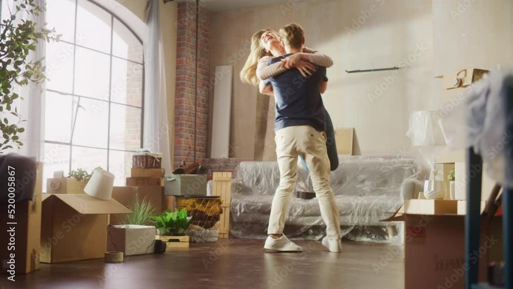 Family New Home Moving in: Happy Girlfriend Returns Home and Finds Her Happy Man Doing Unpacking, They Hug and Dance. Happy Couple in their Cozy Sunny Apartment. Mortgage Loan, Home Renovations Family New Home Moving in: Happy Girlfriend Returns Home and Finds Her Happy Man Doing Unpacking, They Hug and Dance. Happy Couple in their Cozy Sunny Apartment. Mortgage Loan, Home Renovations