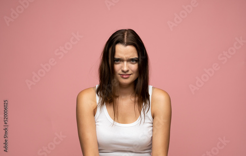 Gloomy insulted timid girl feeling offended and displeased, pouting upset on a pink background.