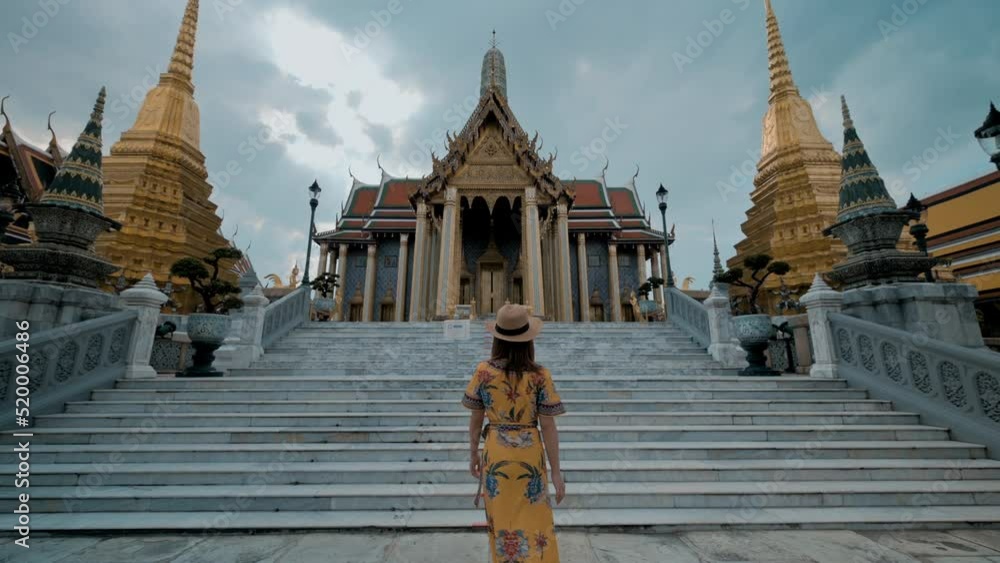 Asian woman in yellow dress traveling at Wat Phra Kaew or Emerald buddha temple in Bangkok Thailand