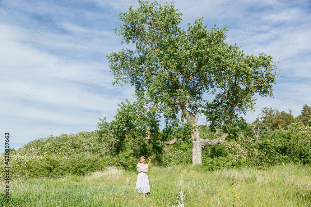 Beautiful girl in a white dress with flowers in a field overlooking the sky Beautiful girl in a white dress with flowers in a field overlooking the sky
