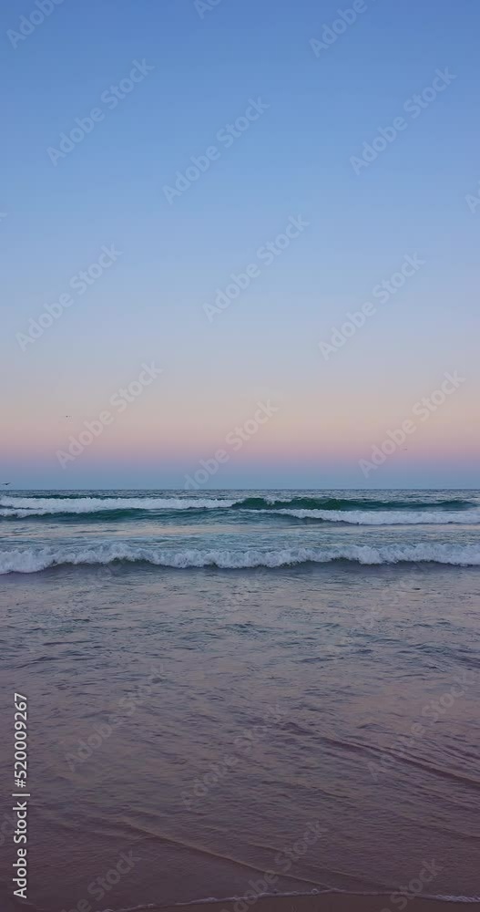 Ocean beach sunset with colorful sky clouds and waves washing sea sand, vertical 4K video Ocean beach sunset with colorful sky clouds and waves washing sea sand, vertical 4K video
