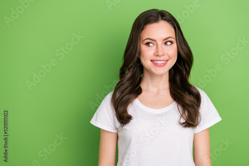 Photo of dreamy pretty young lady wear white t-shirt smiling looking empty space isolated green color background